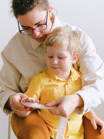 Home A mother attentively applies first aid to her young son indoors.