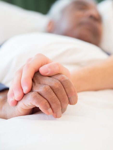 A comforting gesture as a hand holds another in a hospital setting, symbolizing care and support.